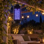 Lampe anti-moustiques suspendue sous une pergola, la nuit, au-dessus dun salon de jardin