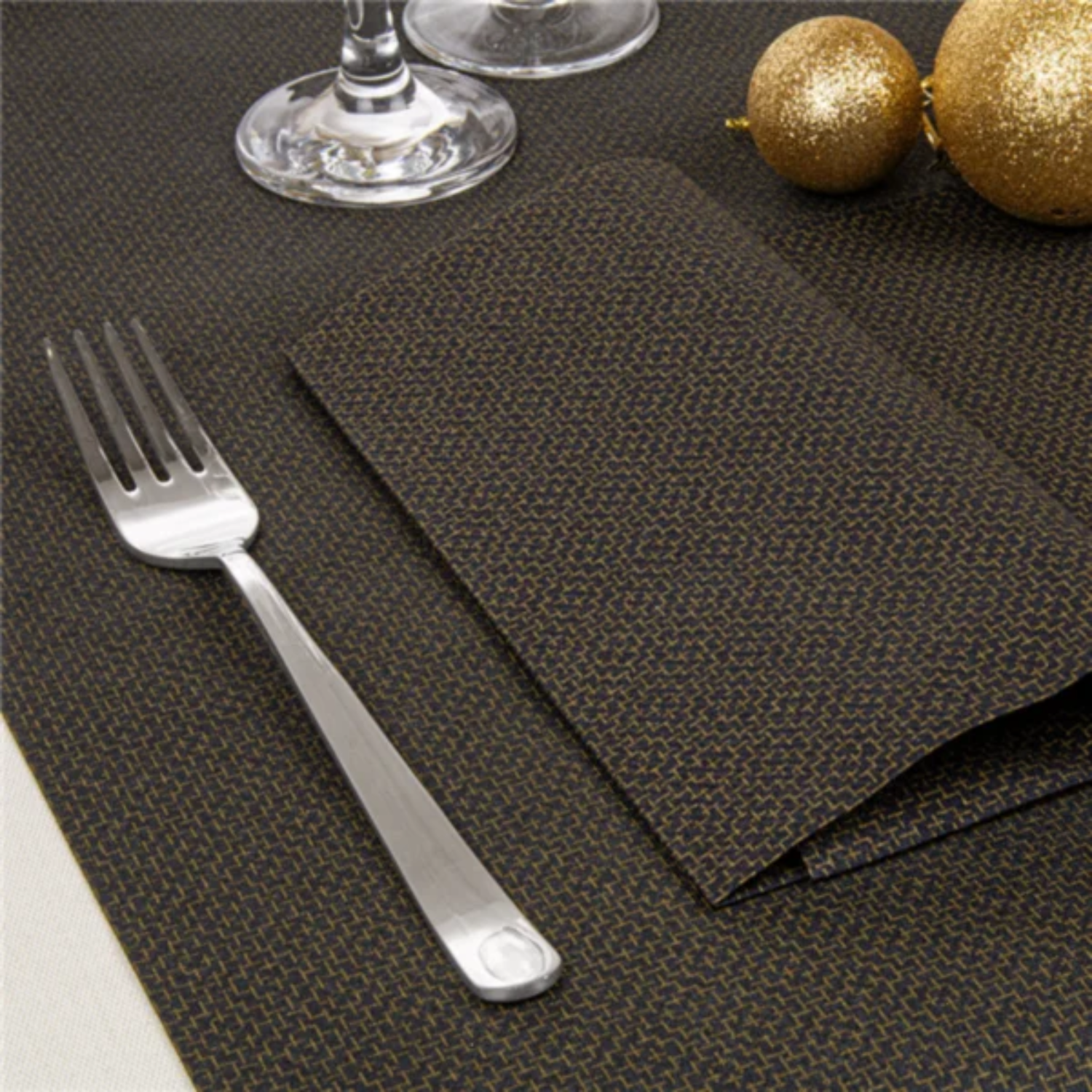Table de Saint-Sylvestre dressée avec la nappe noire à motif doré, assiettes, couverts et décorations