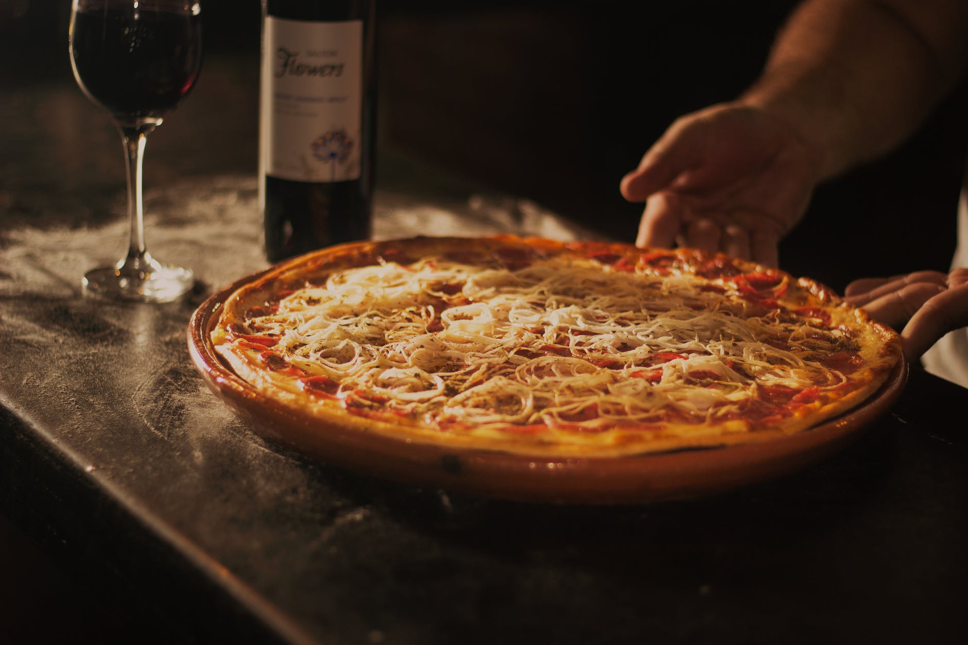personne tenant une pizza au pepperoni sur plateau