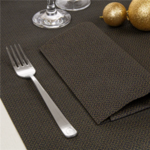 Table de Saint-Sylvestre dressée avec la nappe noire à motif doré, assiettes, couverts et décorations
