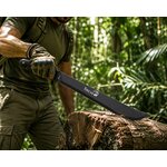 Machette Toucan noire enfoncée dans un tronc darbre en forêt, idéale pour le débroussaillage, la survie et les activités outdoor.