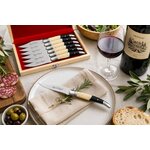 Couteau de table Laguiole Bougna avec manche noir et ivoire présenté sur une assiette élégante lors dun repas gastronomique.