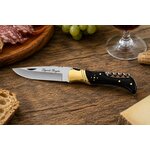 couteau laguiole corne noire de prestige posé sur table de dégustation avec vin fromage et charcuterie