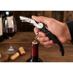 Tire-bouchon sommelier professionnel utilisé par une main d’homme pour ouvrir une bouteille de vin rouge.