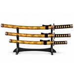 Set de 3 katanas japonais jaune doré sur présentoir noir avec poignées tressées et fourreaux décorés