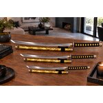 Ensemble de sabres japonais jaune doré exposé sur table en bois dans un intérieur moderne