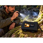 Aventurier utilisant une lampe avec mallette de survie en forêt