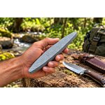 Pierre à aiguiser Albainox 21,5 cm tenue dans la main dun homme en forêt, avec couteau de randonnée en arrière-plan.