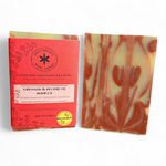 Savon Grenade et Beurre de Mangue artisanal, avec son emballage rouge et sa barre marbrée rouge et ivoire.